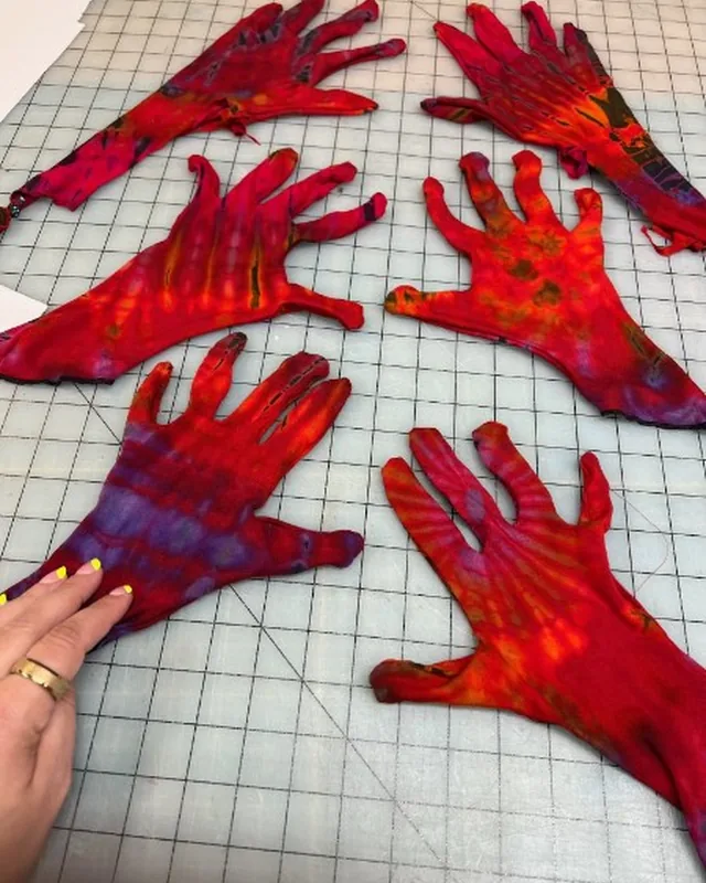 Hand-dyed red fabric gloves laid out on a cutting mat