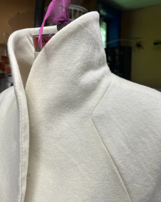 Cream coat collar detail pinned on a form