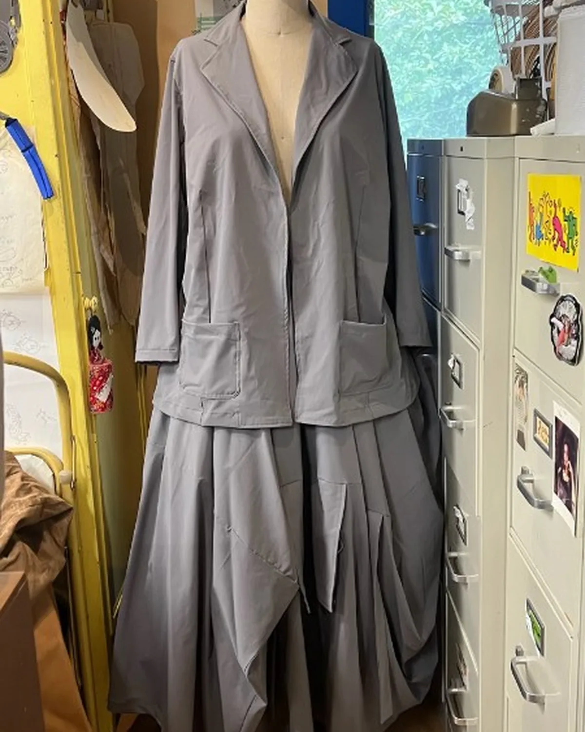 Gray tailored jacket and pleated skirt ensemble on a dress form