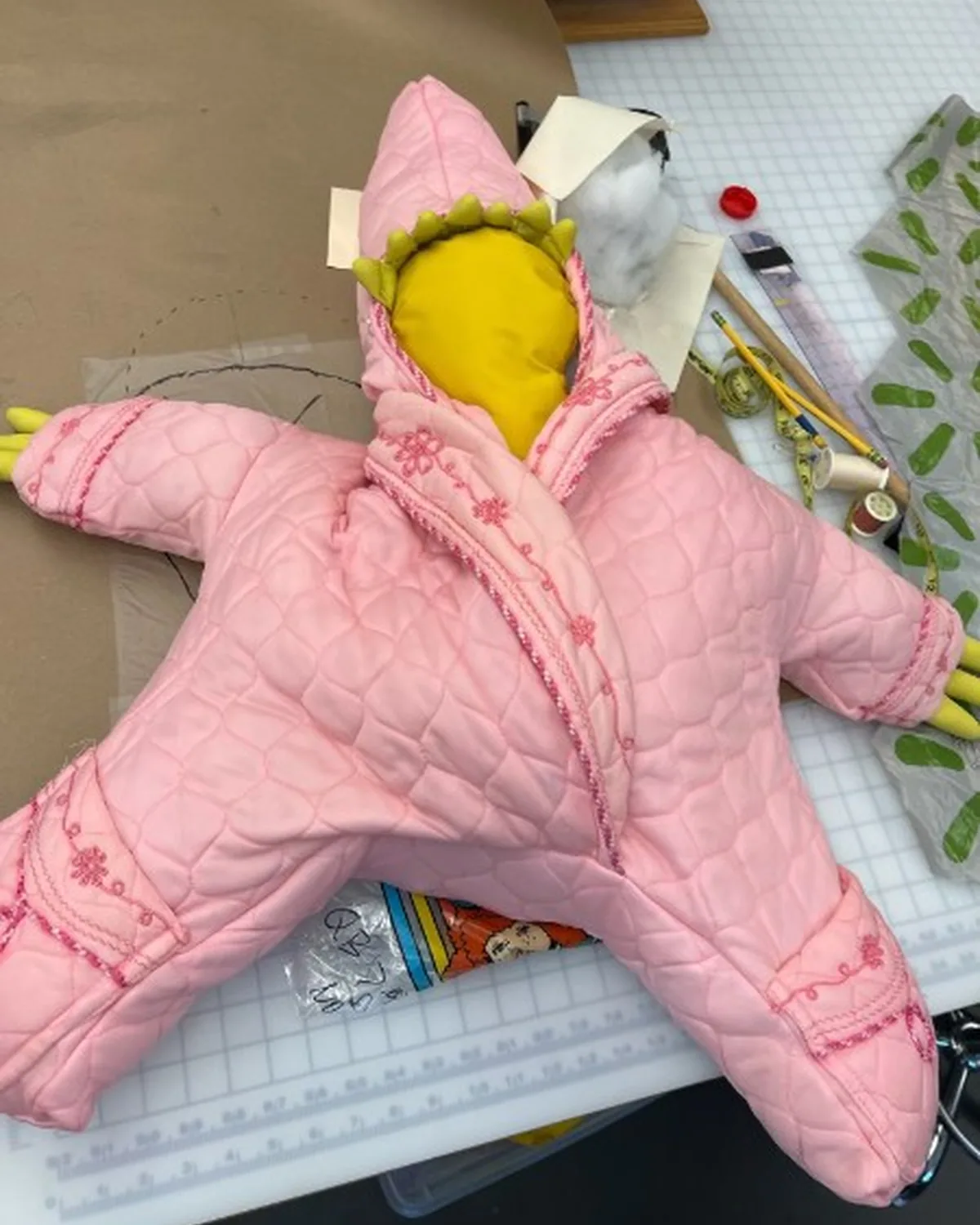 Pink quilted star-shaped character suit under construction on the worktable